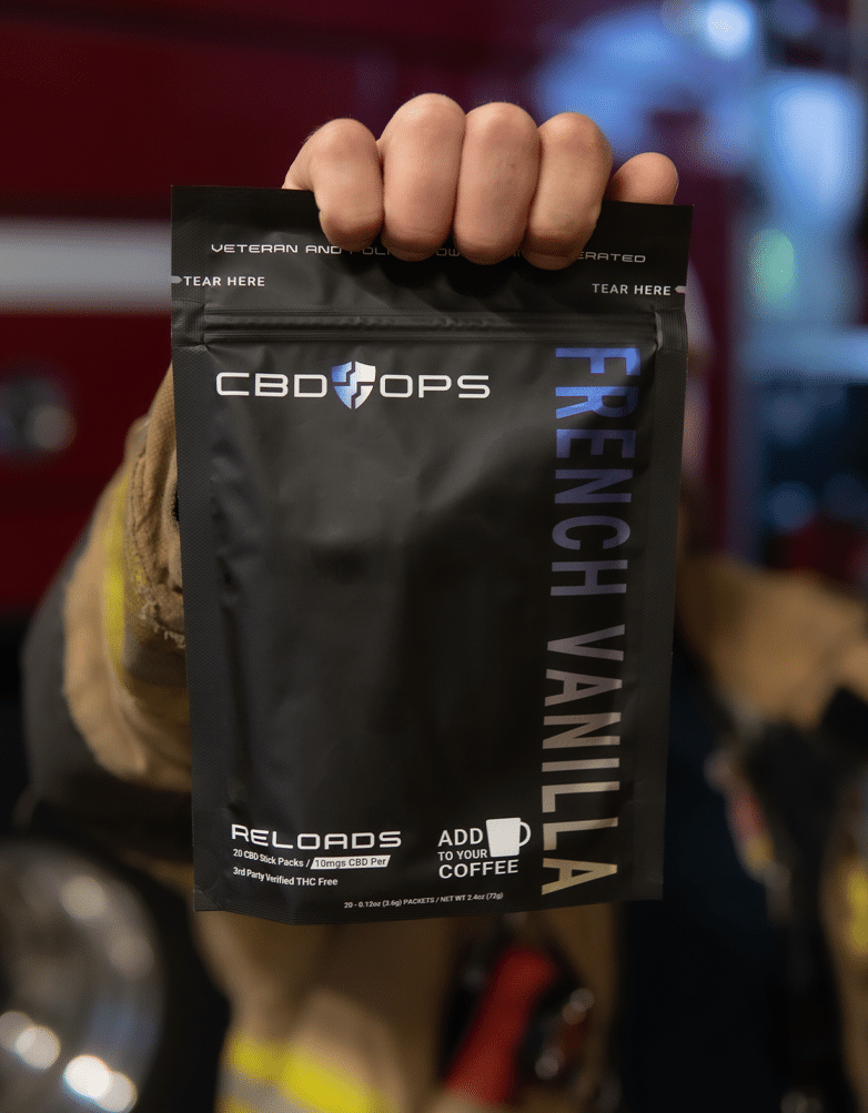 Firefighter holding up their CBDops french vanilla CBD powder packets for coffee flavoring product.