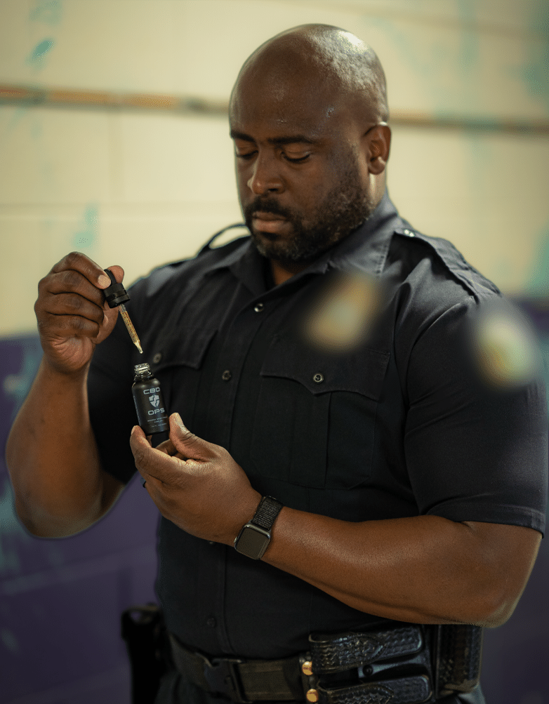 Male police officer applying CBD tincture oil and confirming CBD is not snake oil.